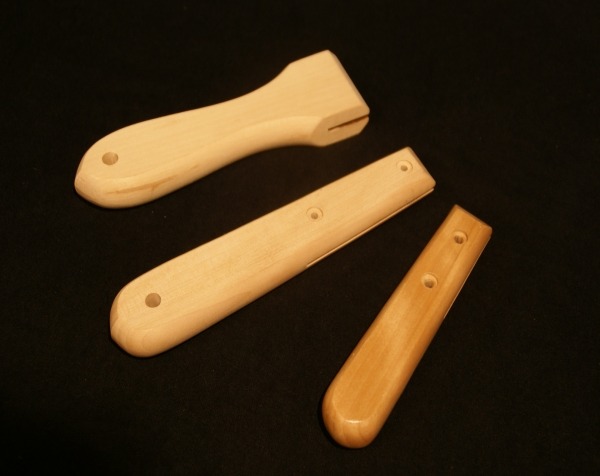 Three flat wooden handles with various secondary operations, including cross bore holes and slotted ends.